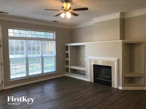 A living room with a fireplace and a ceiling fan.
