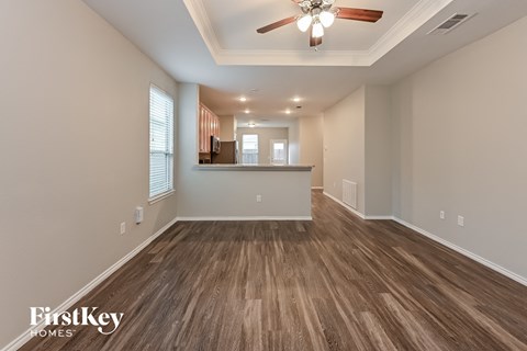 A spacious room with wooden flooring and a ceiling fan.