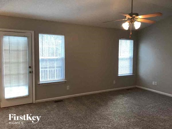 A room with a ceiling fan and two windows.