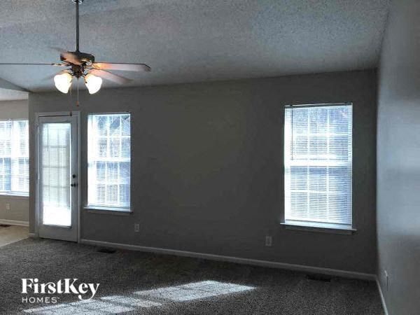 A room with a ceiling fan and two windows.