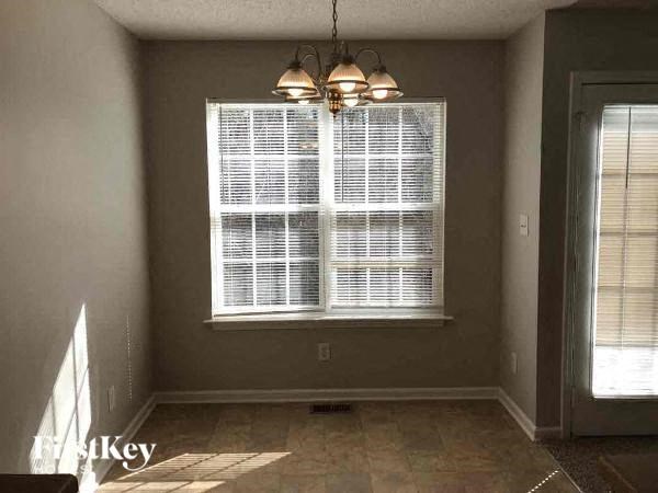 A room with a window covered in blinds and a light fixture hanging from the ceiling.
