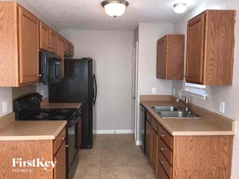 A kitchen with wooden cabinets and a black refrigerator.