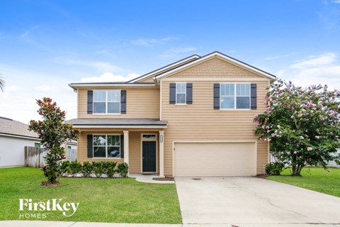 a beige house with a garage door and a lawn