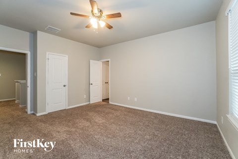 a spacious living room with carpet and a ceiling fan