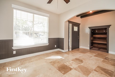 an empty living room with a large window and a door to a staircase