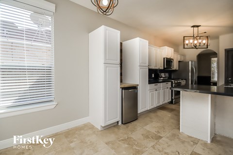 a kitchen with white cabinets and stainless steel appliances and a large window