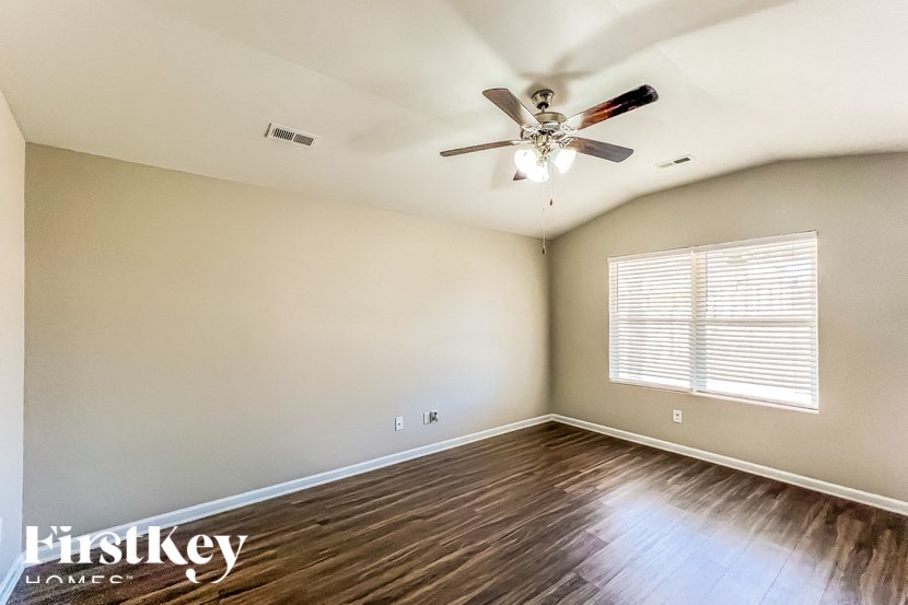 A room with a ceiling fan and wooden flooring.