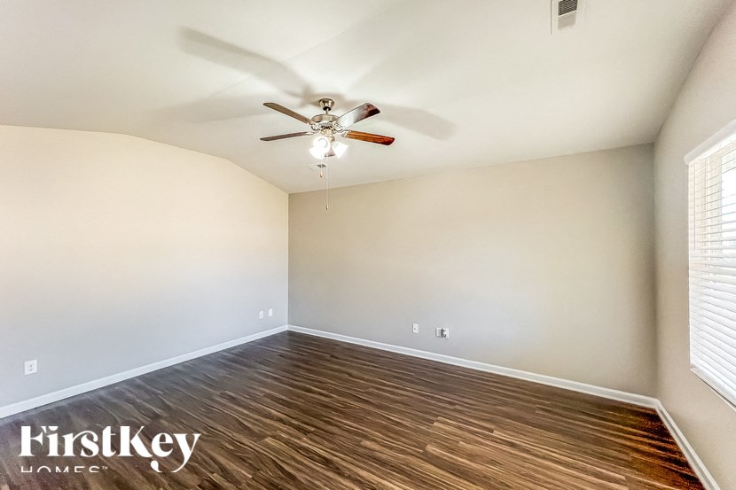 A room with a ceiling fan and wooden flooring.