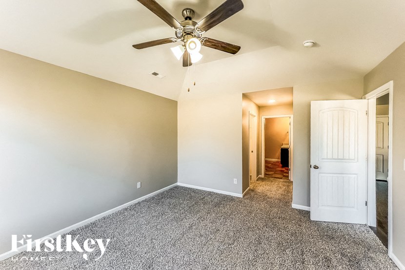A spacious room with a ceiling fan and carpeted floor.