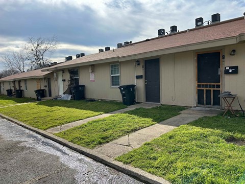 the front of a white building with grass and a sidewalk