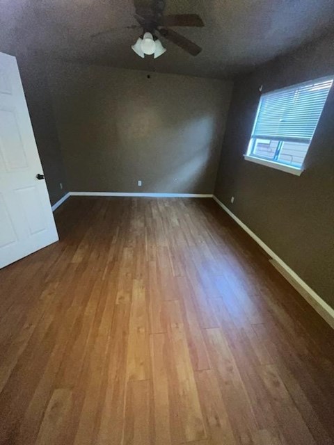 a empty room with a wood floor and a ceiling fan