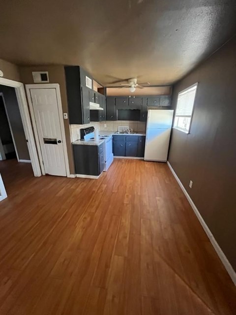 an empty living room and kitchen with wood floors
