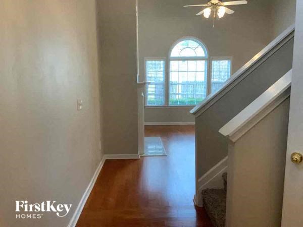 A hallway with a staircase leading to a landing with a window.