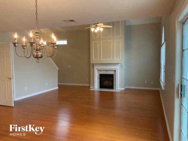 A large empty room with a fireplace and a chandelier.