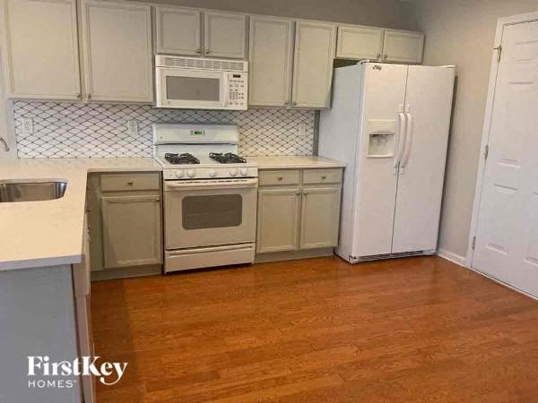 A kitchen with wooden floors and white appliances.