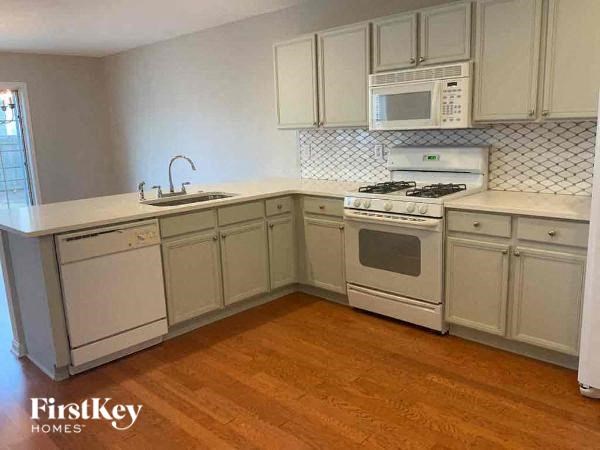 A kitchen with wooden floors and white appliances.