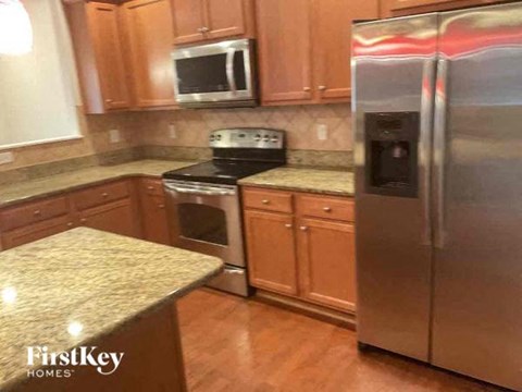 A kitchen with wooden cabinets and a stainless steel refrigerator.