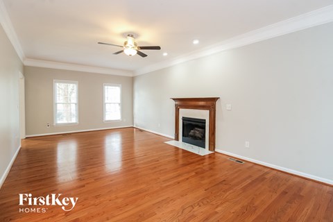 A spacious room with a fireplace and wooden floors.