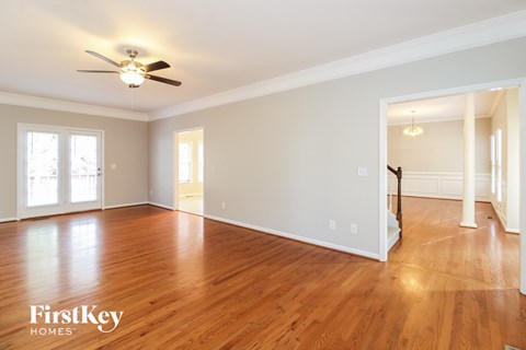 A spacious room with wooden floors and a ceiling fan.