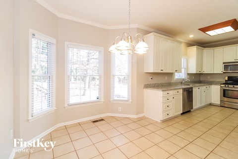 A kitchen with white cabinets and a tile floor.