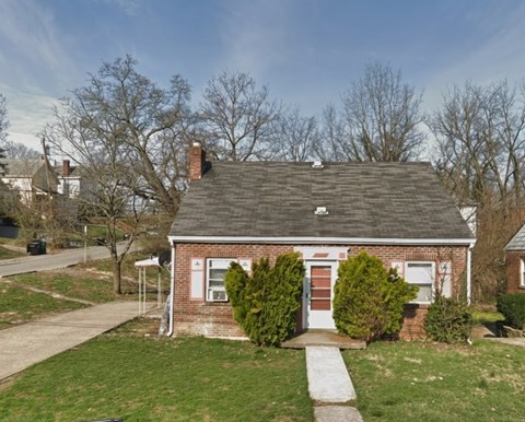 A small brick house with a red door and a chimney.