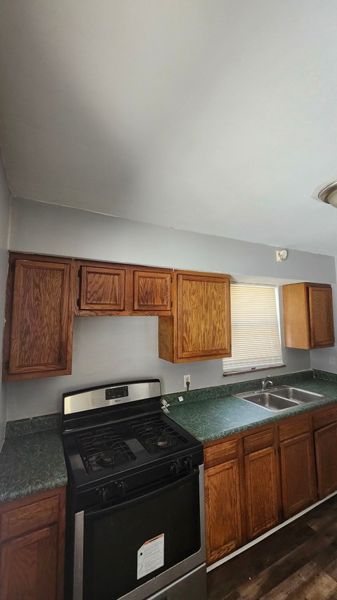 A kitchen with wooden cabinets and a black stove top oven.