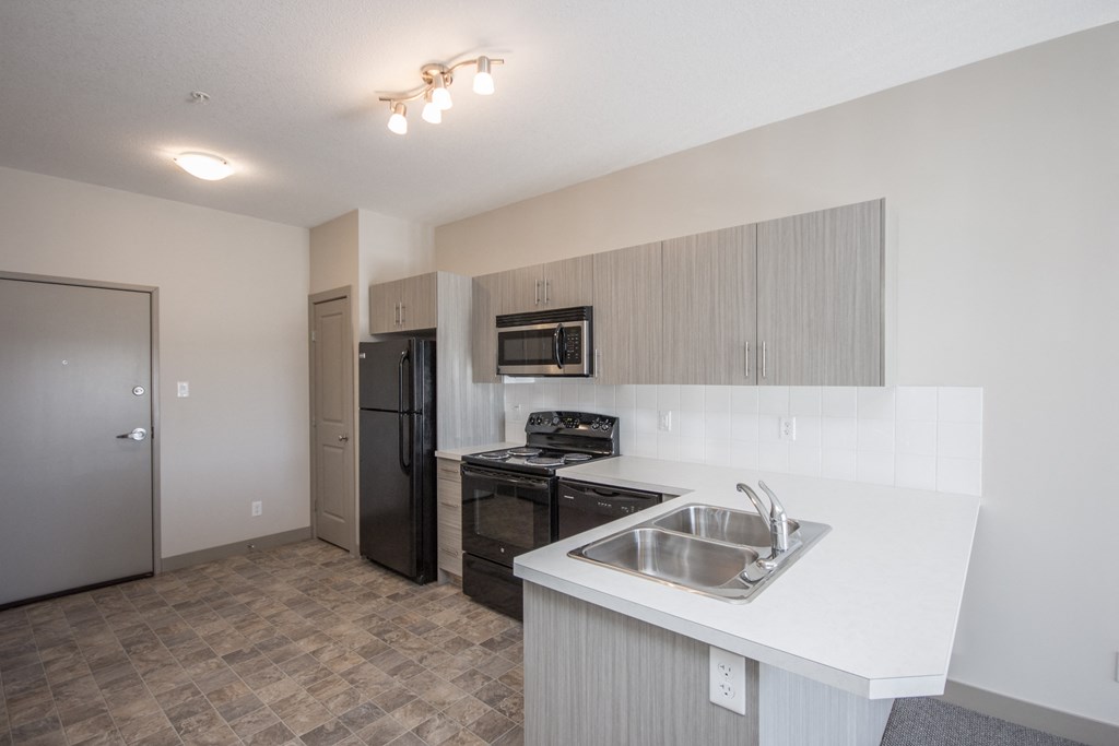 A kitchen with a sink, stove, and refrigerator.
