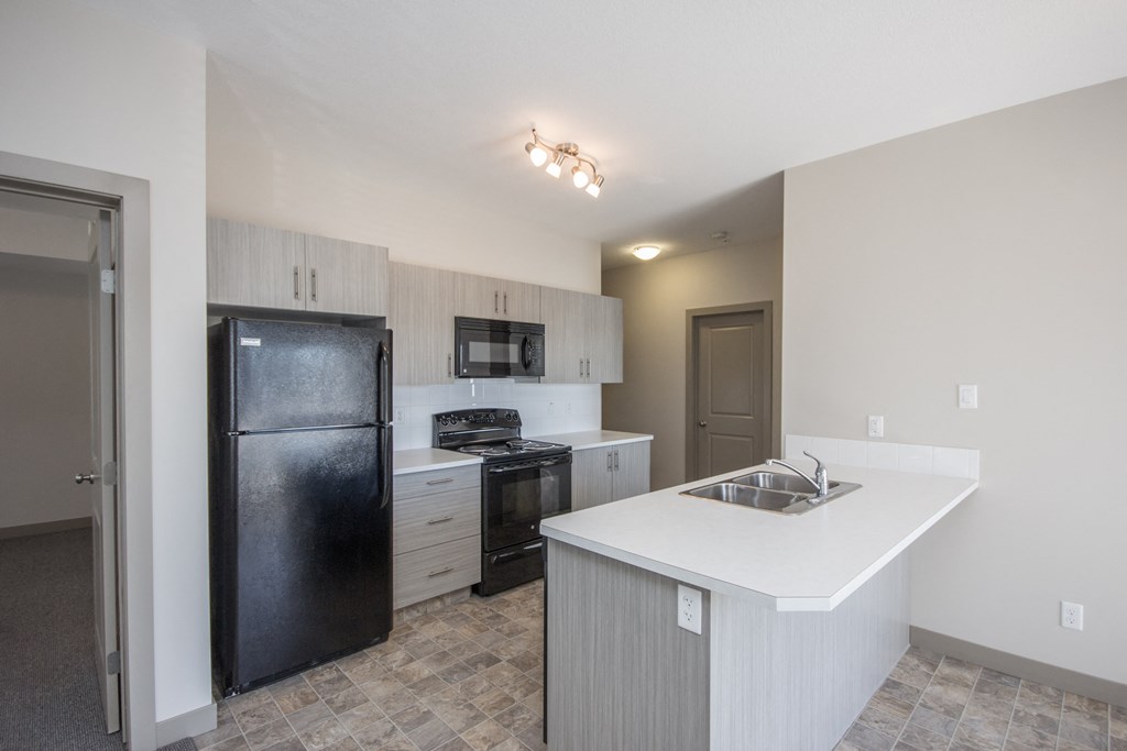 A kitchen with a black refrigerator, microwave, and stove top oven.