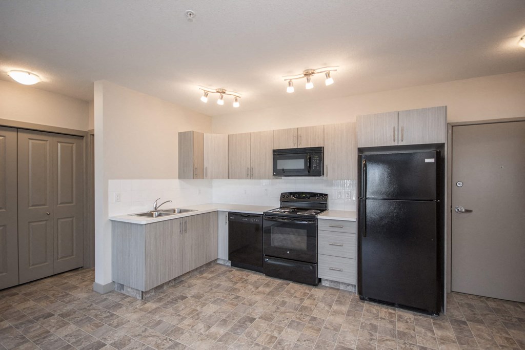 A kitchen with black appliances and a tiled floor.