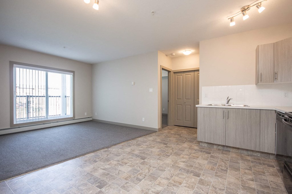 A spacious living room with a kitchenette and a large window.