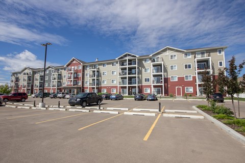 A parking lot in front of a multi-story apartment building.