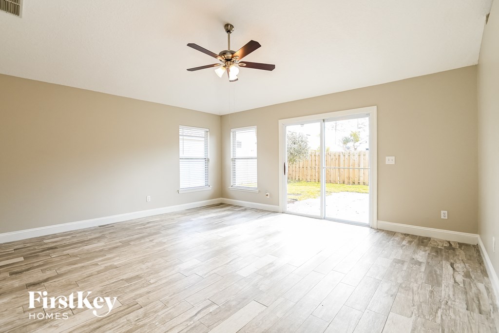 an empty living room with a ceiling fan and a sliding glass door