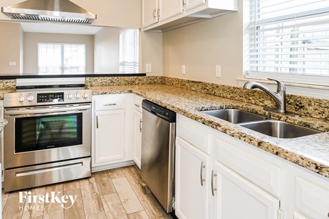 a kitchen with white cabinets and granite counter tops and stainless steel appliances