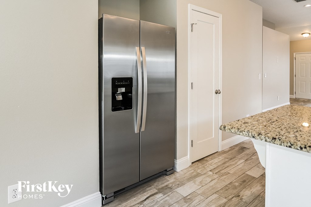 a kitchen with a stainless steel refrigerator and a door to a closet