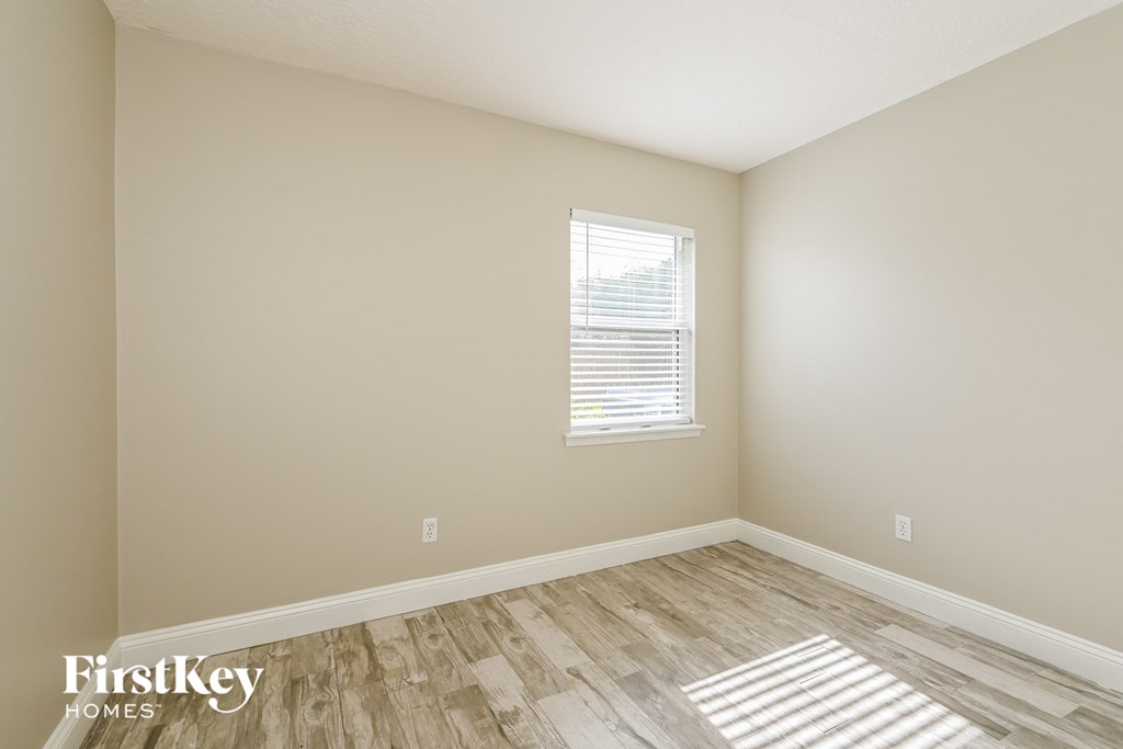 the second bedroom with wood flooring and a window
