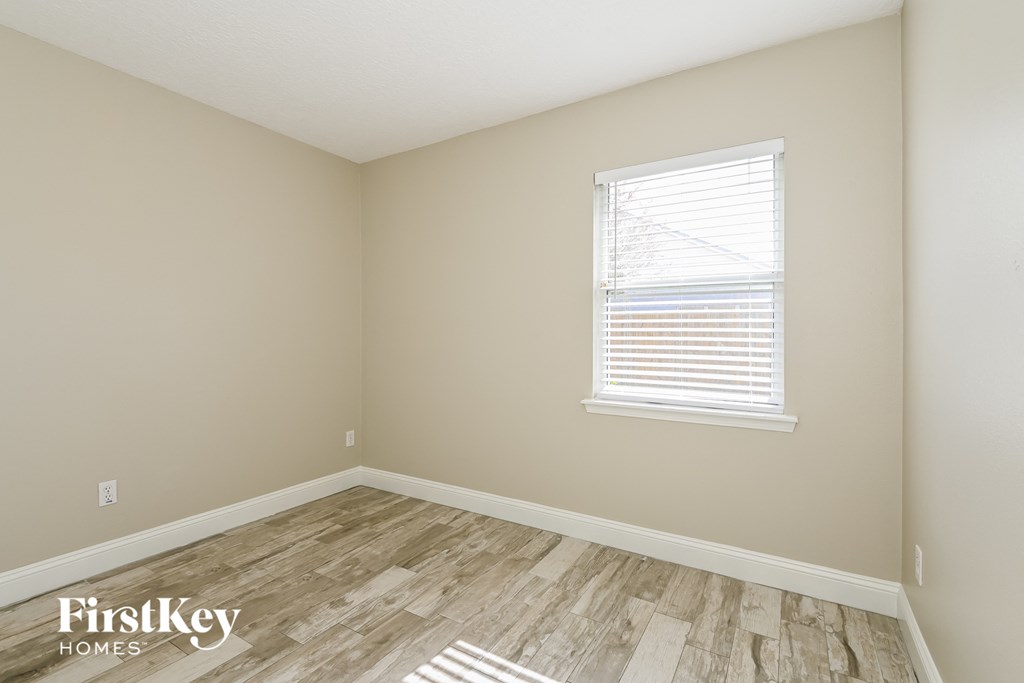 the second bedroom with wood flooring and a window