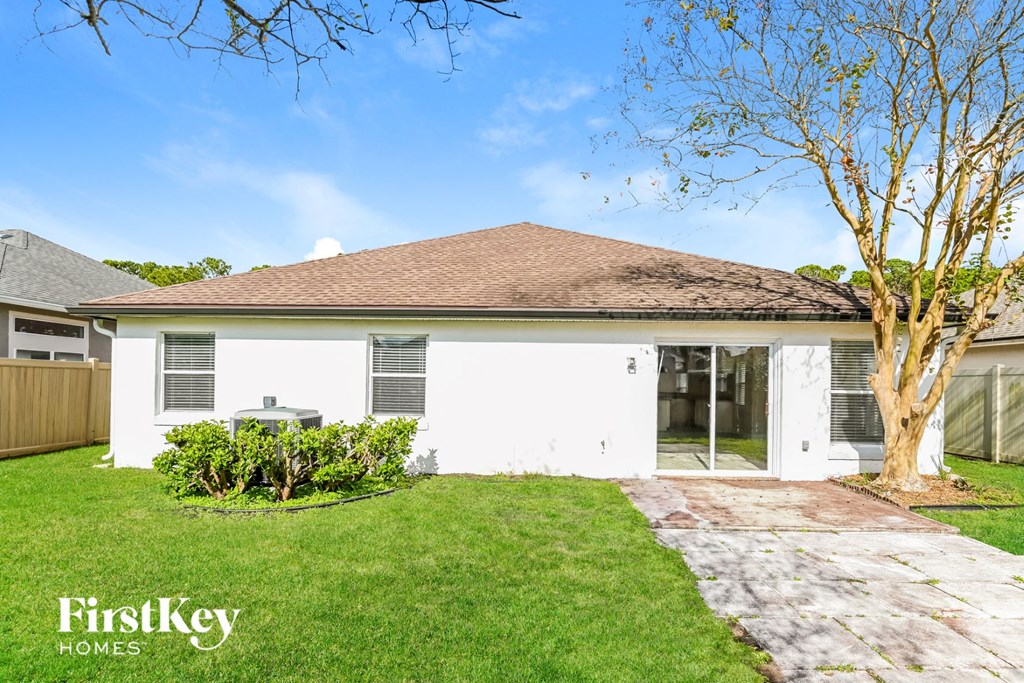 a white house with a lawn and a tree