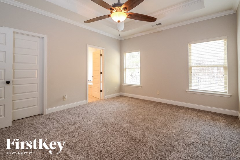 A spacious room with a ceiling fan and carpeted floor.