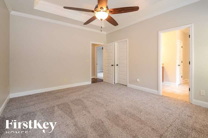 A room with a carpeted floor and a ceiling fan.