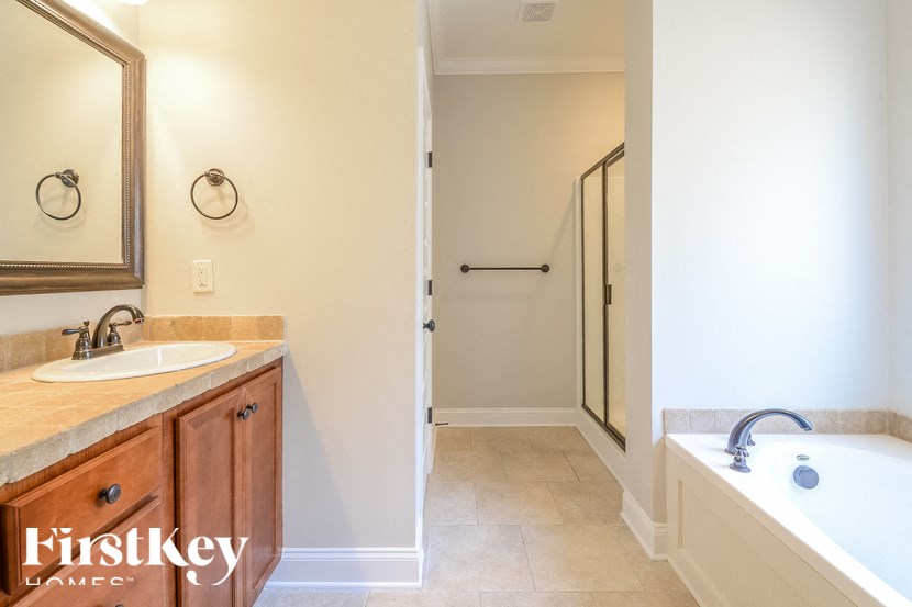 A bathroom with a tub, sink and mirror.