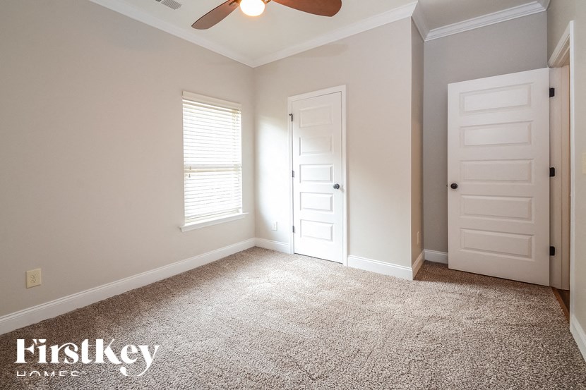 A room with a carpeted floor and a ceiling fan.
