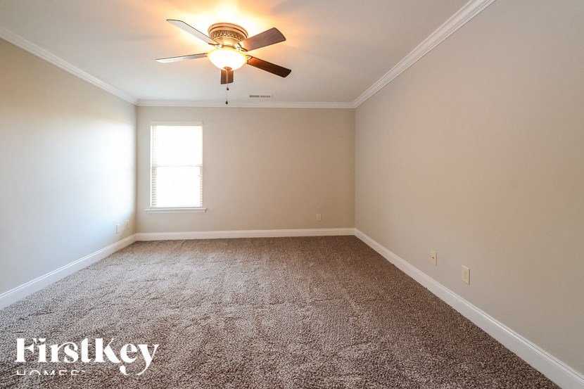 A room with a ceiling fan and carpeted floor.