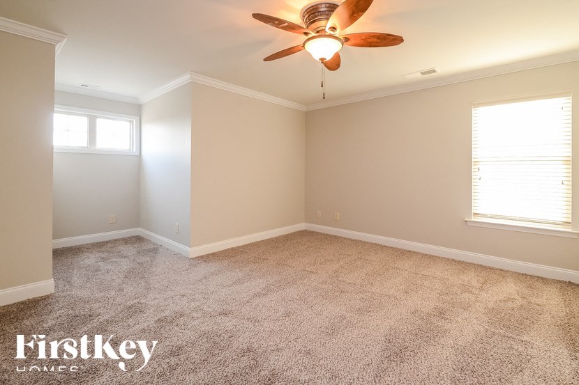 A room with a ceiling fan and carpeted floor.