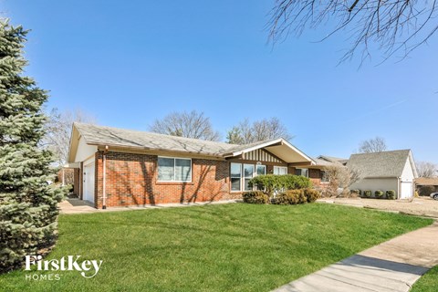 a brick house with a green lawn and a sidewalk