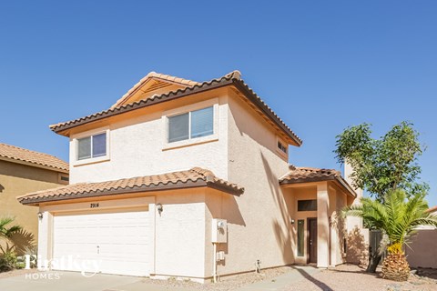 a white house with a garage and a palm tree