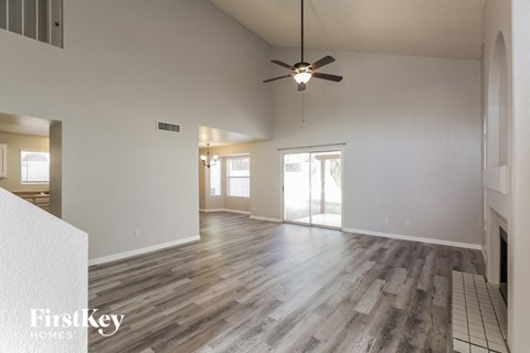 the living room and dining room of an empty house with a ceiling fan