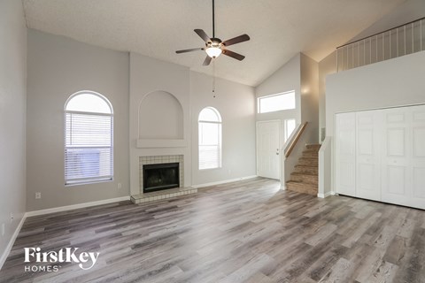 an empty living room with a fireplace and a ceiling fan