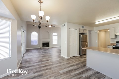 a living room and kitchen with a fireplace and a chandelier