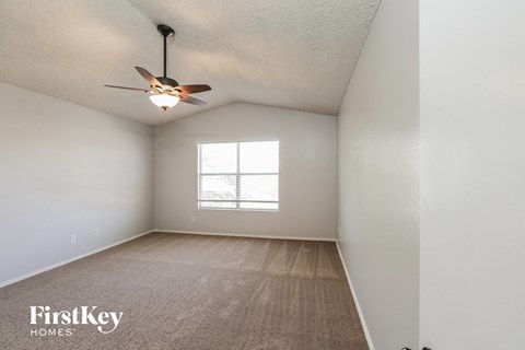 an empty room with a ceiling fan and a window