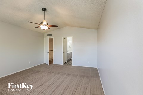 a spacious living room with white walls and a ceiling fan